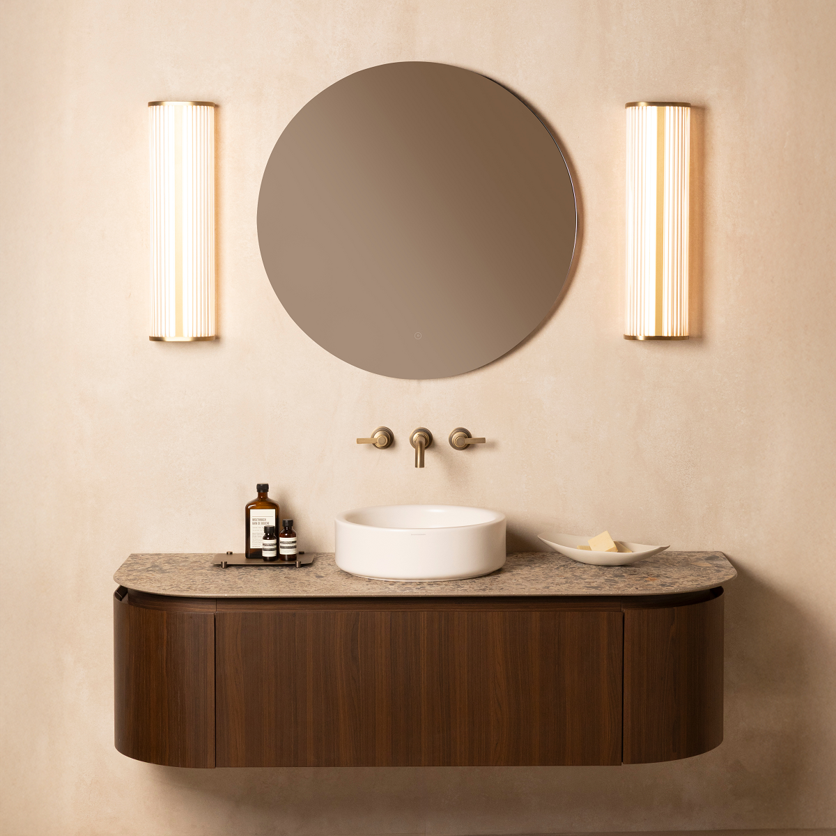 round mirror flanked by lights above floating vanity
