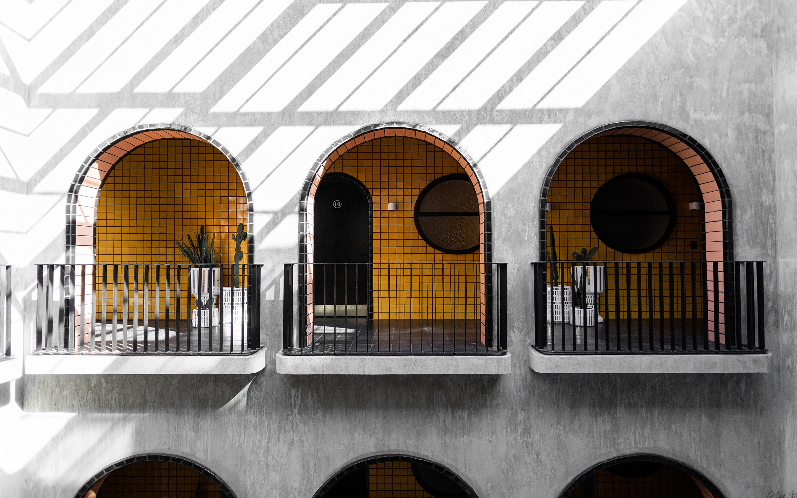 concrete wall with three arches through to bright yellow tiles at Casa Hoyos