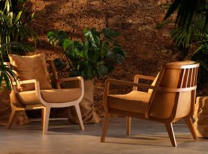 two wooden Kaya chairs by Morgan with plants and brown backdrop