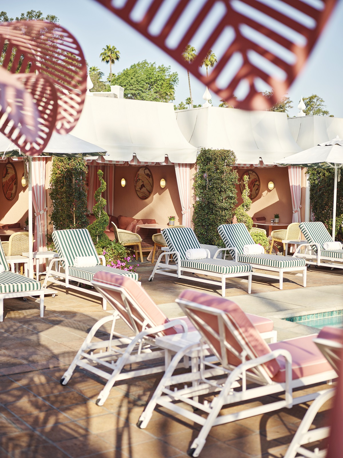 sunloungers around the pool with Beverly Hills Hotel Cabanas. by Champalimaud Design