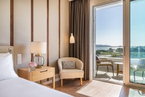 view from the bed with bedside table and chair opening onto terrace with river views in guestroom at Hyatt Regency Lisbon.