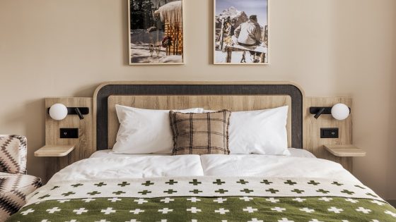 wooden bed with green and white bedlinen in Faern Arosa Altein guestroom