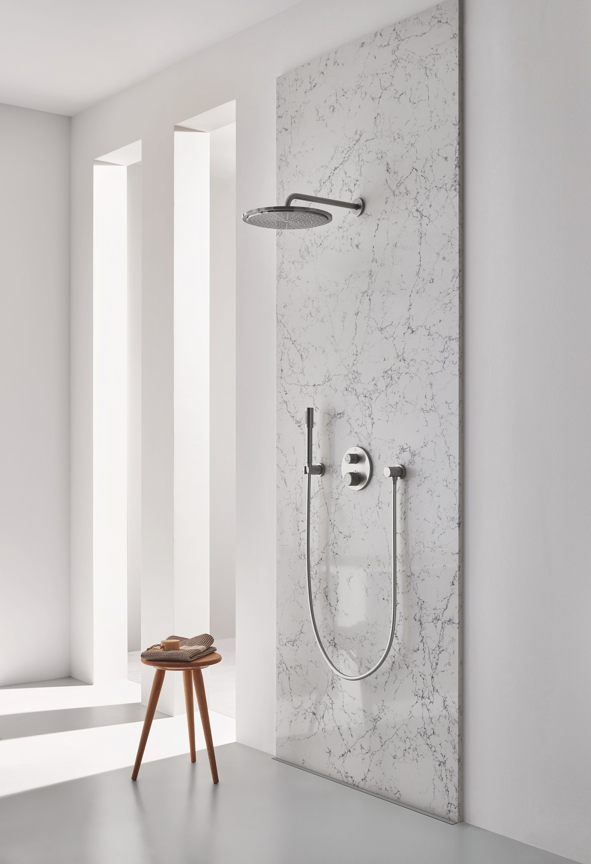 wooden stool in spa shower with a marble wall and GROHE Atrio shower system