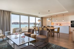 coffee table and chairs in front of dining table and kitchen with river views in guest suite in Hyatt Regency Lisbon.