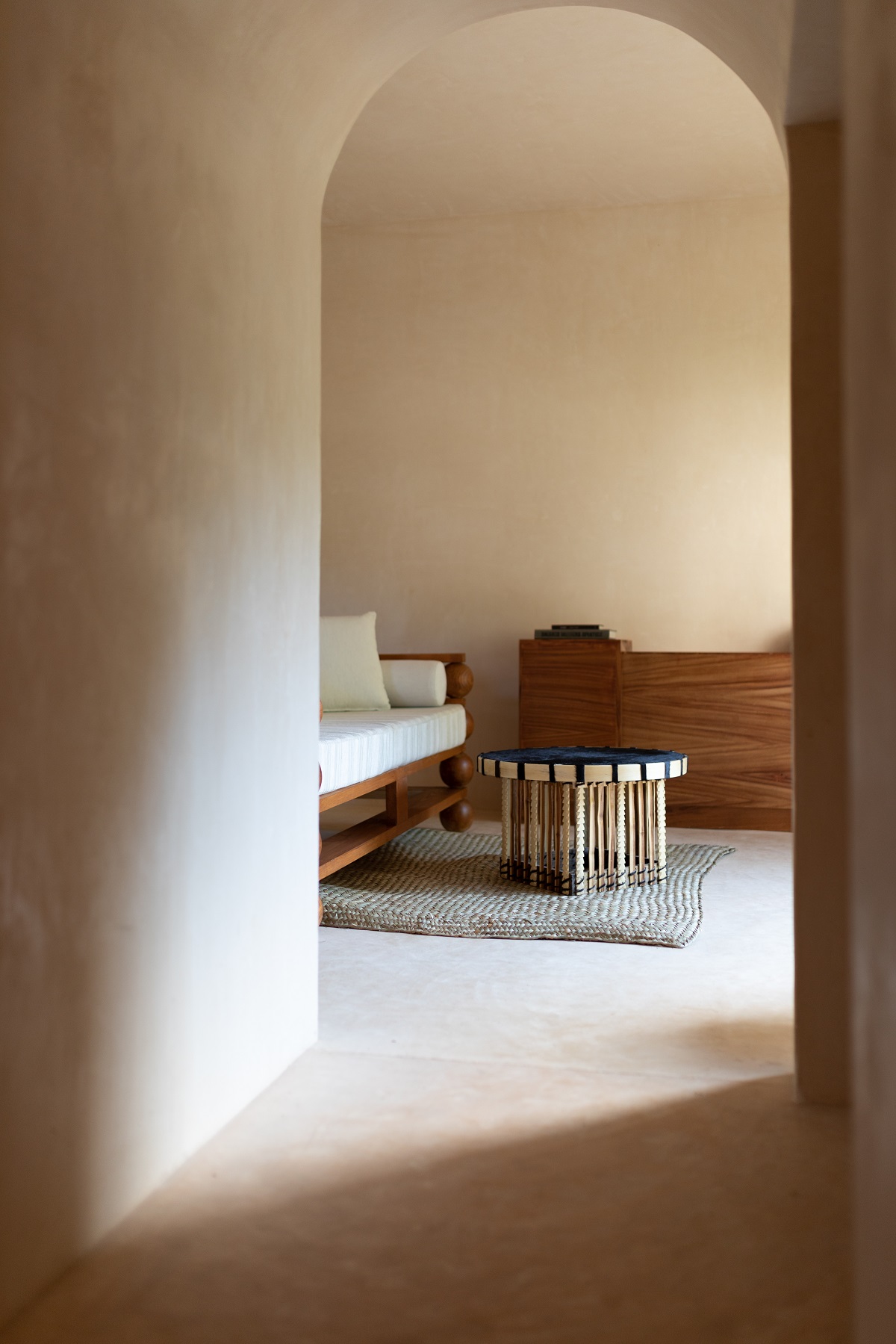 natural plaster forming an organic arched doorway with a view onto handcrafted table and chair