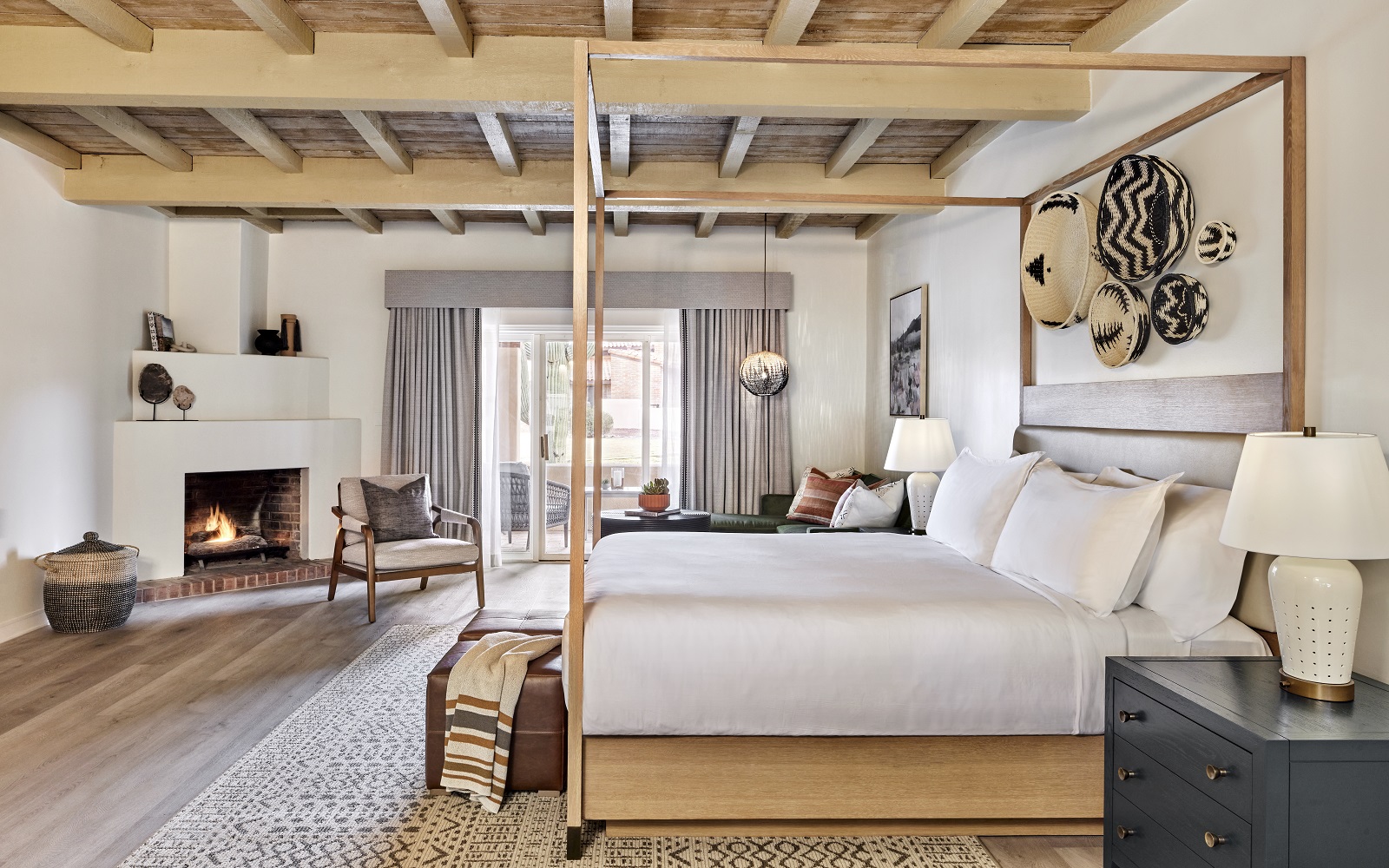 rustic wooden four poster bed with baskets on the wall and a fireplace in Omni Tucson National Resort