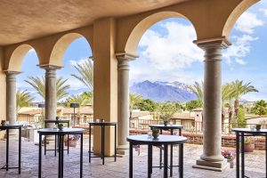 chairs and tables under an arched terrace at Omni Tucson National Resort with views across to the golf course and mountains
