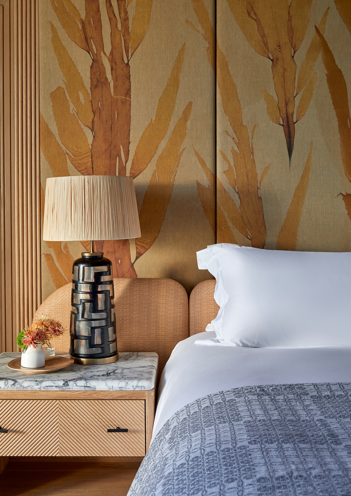 guestroom at One&Only Cape Town with design details by Muza Lab of wallpaper inspired by kelp and handmade crafts next to the bed