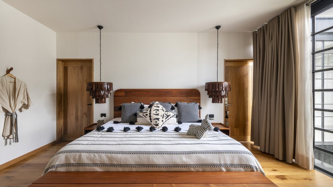 guestroom in hotel Majagua with black and white woven bedcover, and wooden surfaces next to floor to ceiling window