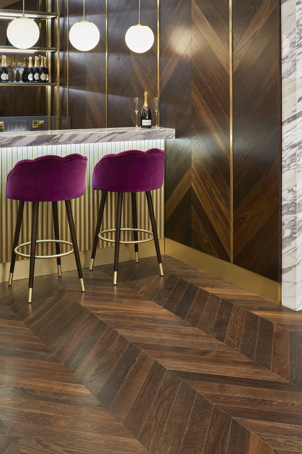 Dark wood flooring in bar with contemporary lighting and pink bar stools