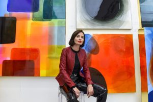 the artist Nat Bowen sitting in front of one of her colourful resin works of art