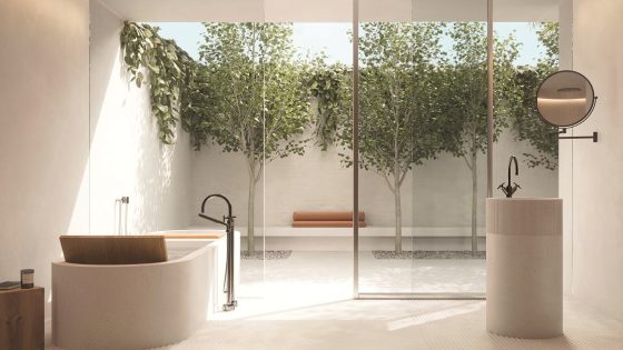 a light and stone coloured spa bathroom with glass doors surrounded by plants. Fittings from Dornbracht