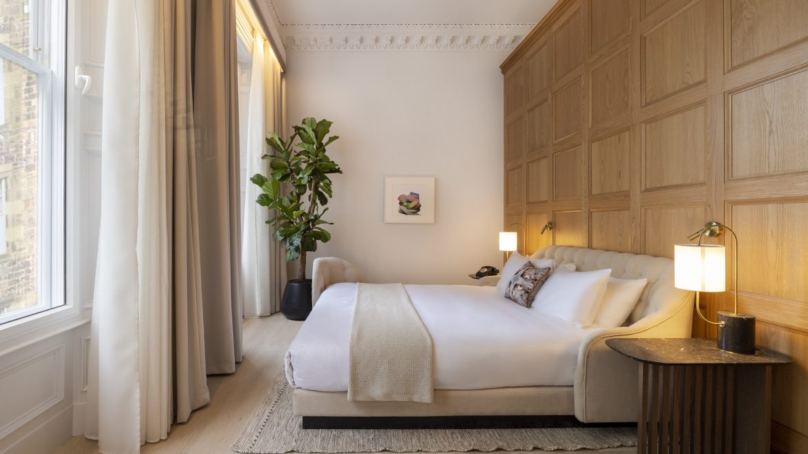 bed with white linen against a wooden panelled wall in guestroom at virgin Hotels Edinburgh