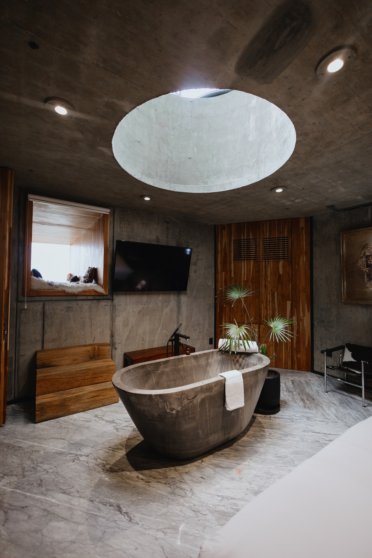 bathroom designed in wood and concrete with concrete freestanding bath directly blow circular window