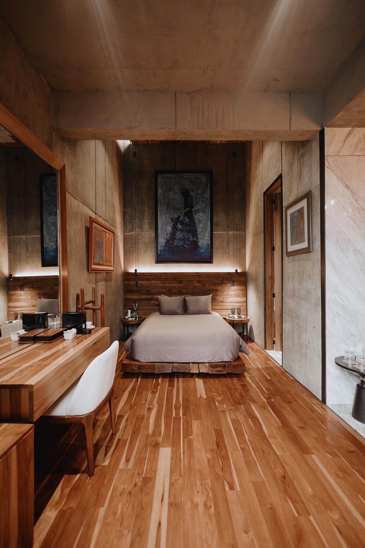 bed in guestroom at hotel Flavia set against concrete walls and on wooden floors