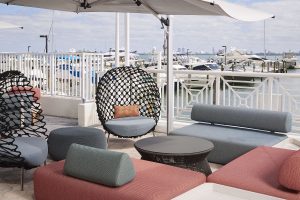 outdoor seating in pink and blue with woven hanging seats overlooking the Miami waterfront