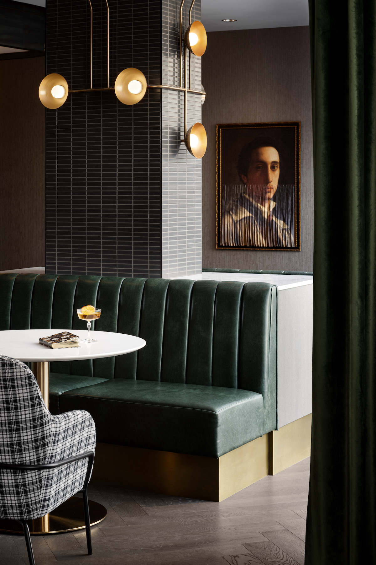 A close-up of restaurant with dark green sofa and image of man on wall as art