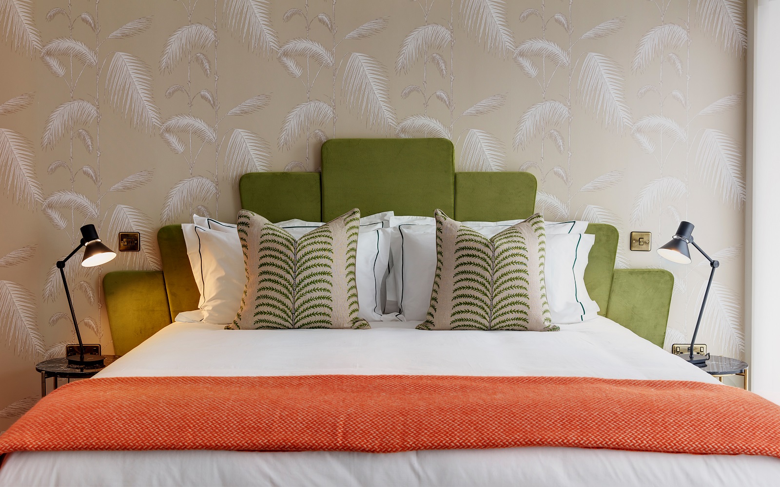 patterned wallpaper, green headboard, orange throw on the art deco style bed in the guestroom at Brama Bromley