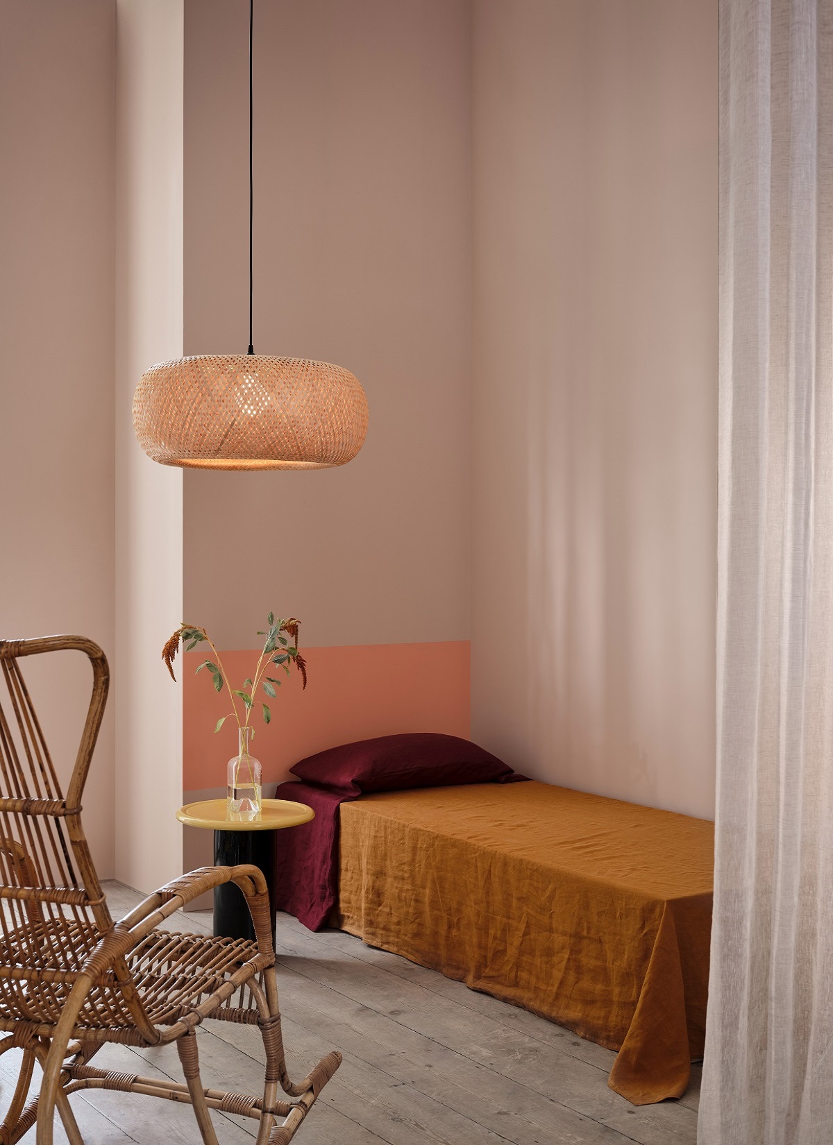 room set with bed and wicker light with wall painted by Graphenstone paints in coral