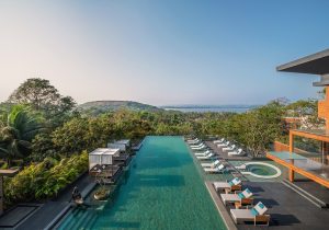swimming pool with sunloungers and cabanas looking out over trees to the sea at JW Marriott Goa