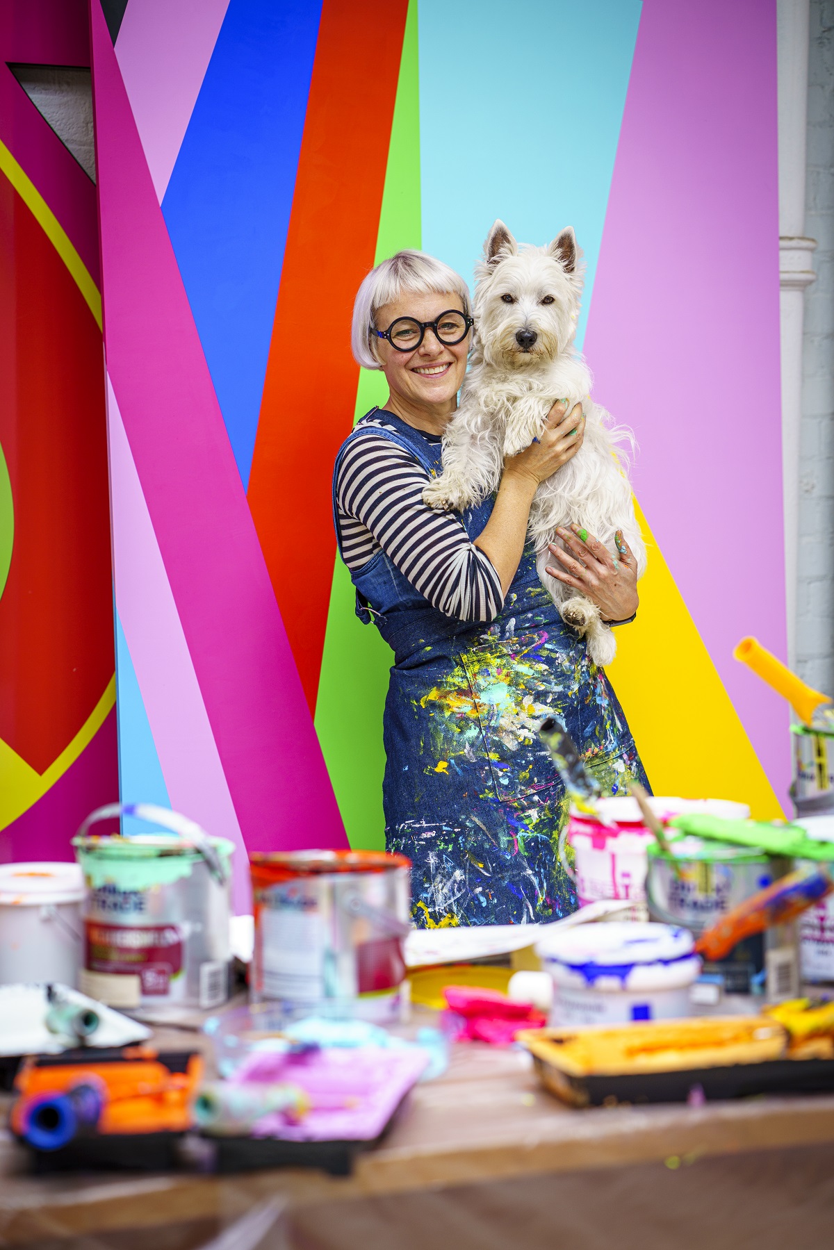 Morag Myerscough against colourful backdrop with small dog
