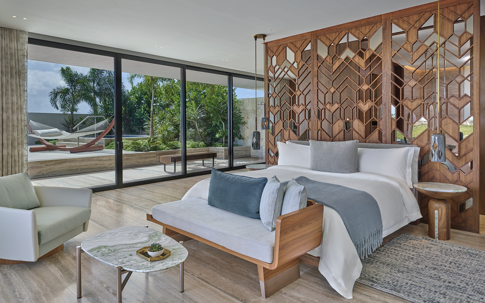 guestroom with wooden headboard divider detail and view to terrace with hammock at St Regis Kanai Resort by Chapi Chapo