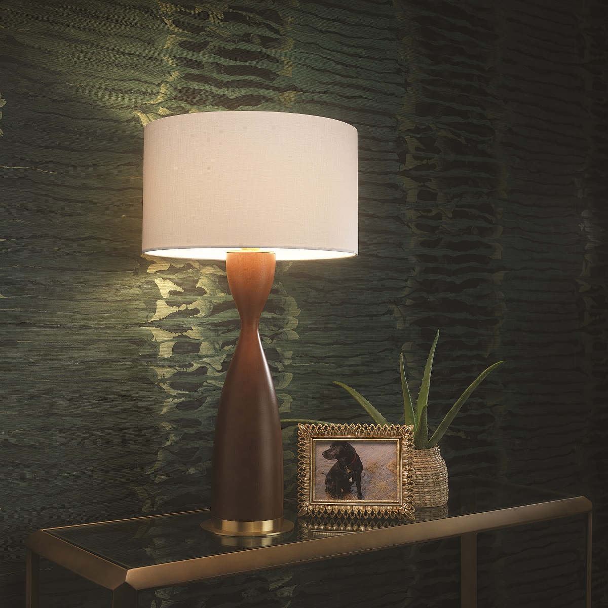 hand turned wooden base table lamp against green wall with plant and frame. Sisley table Light by Northern Lights