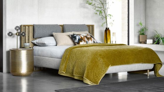wood and upholstered bed with mustard throw and grey concrete floor. Bed design by sofa.com