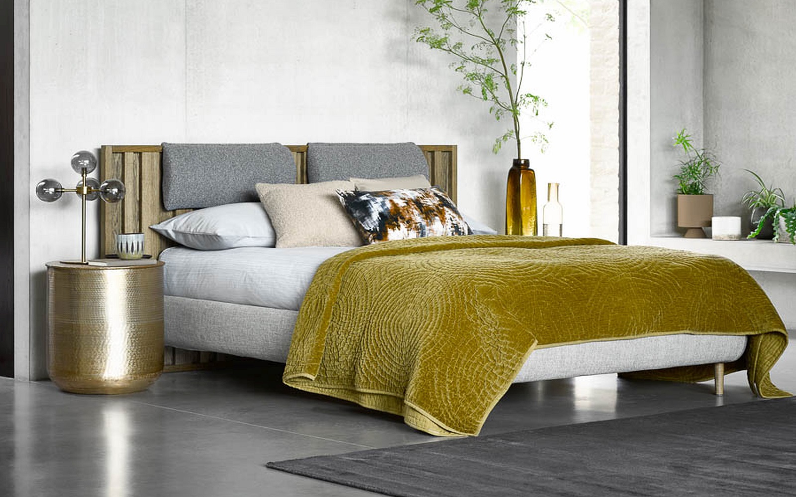 wood and upholstered bed with mustard throw and grey concrete floor. Bed design by sofa.com