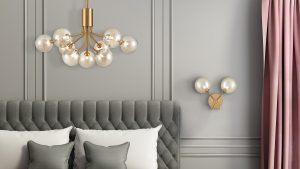 Cosmic bubble chandelier with gold finish against grey wall and above grey and white bed setting