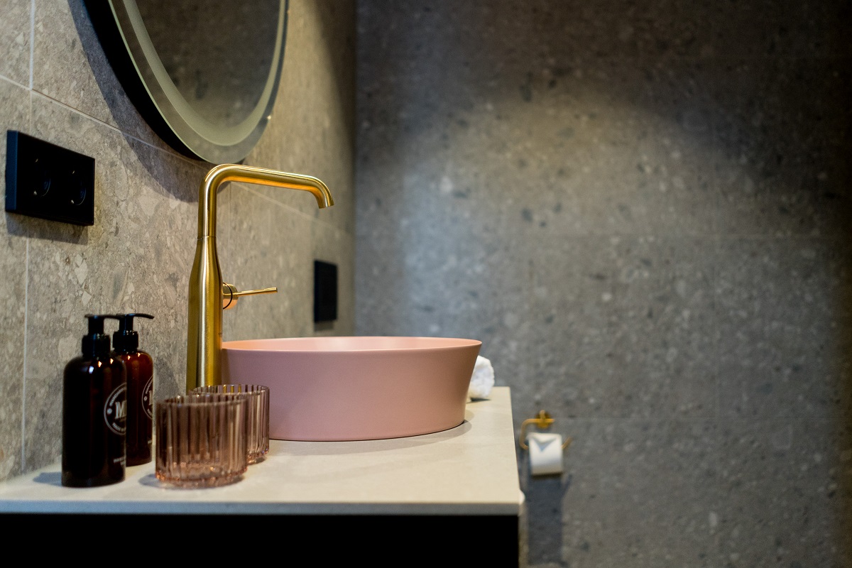 stone walls and pink handbasin with gold tap in Bob W bathroom in Munich