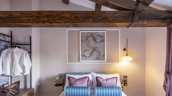 Bedroom inside luxury apartment in Venice with wooden beams over ceiling