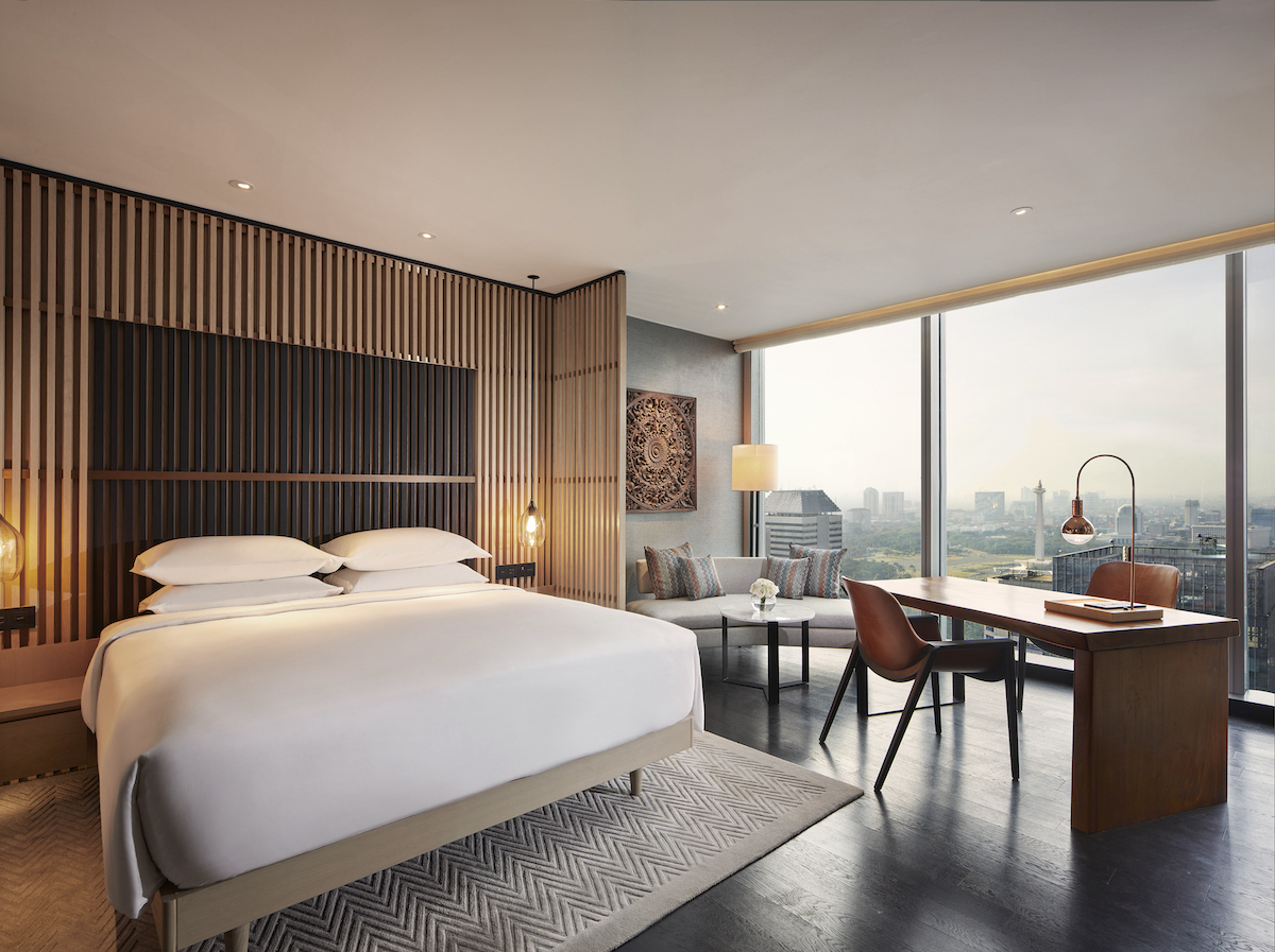 Modern, contemporary guestroom in hotel with wooden headboard and walls