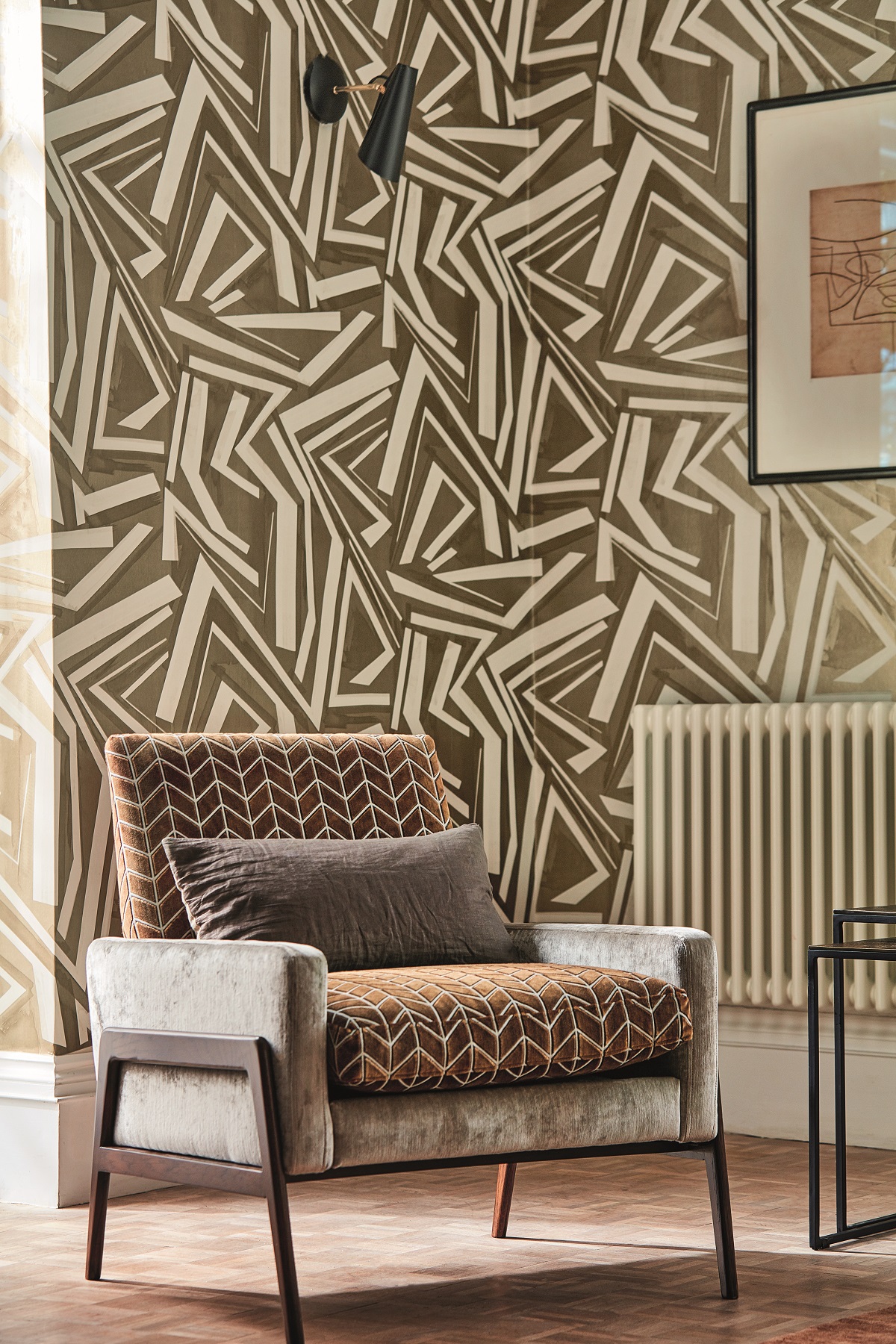 contemporary chair upholstered in brown geometric contract velvet fabric by Harlequin in front of bold brown geometric wallpaper