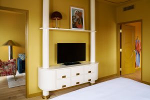 saturated yellow guestroom in Hotel Genevieve with curved furniture and a view through to yellow bathroom