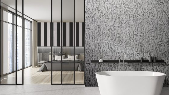 bathroom with patterned Newmor wallpaper and bedroom through black glass doors