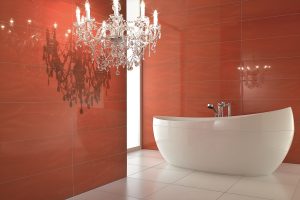 organic round freestanding villeroy & boch bath against a red wall with a crystal chandelier for lighting