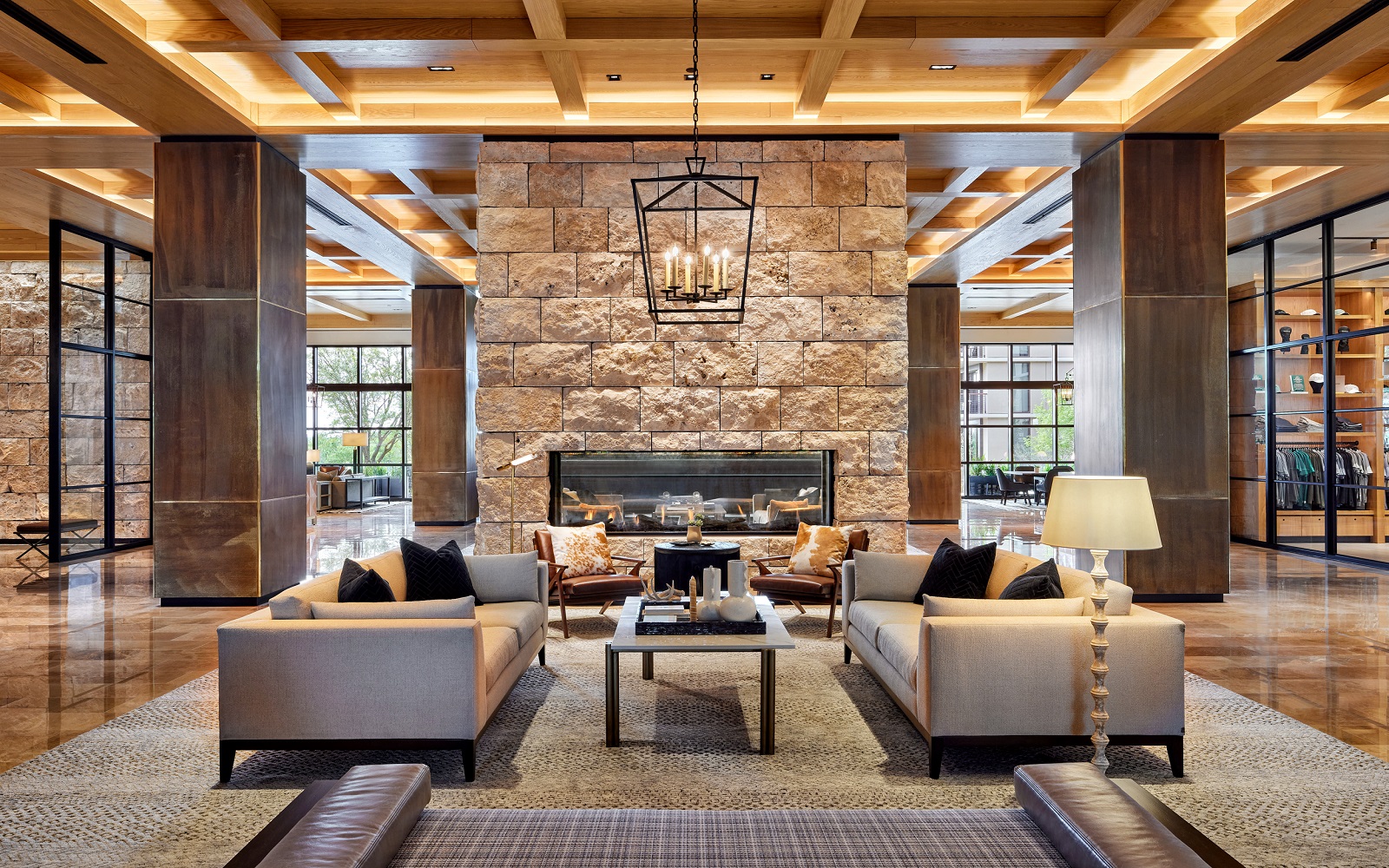 central stone fireplace with seating below ranch style wooden beams in the lobby of Omni PGA Frisco Resort