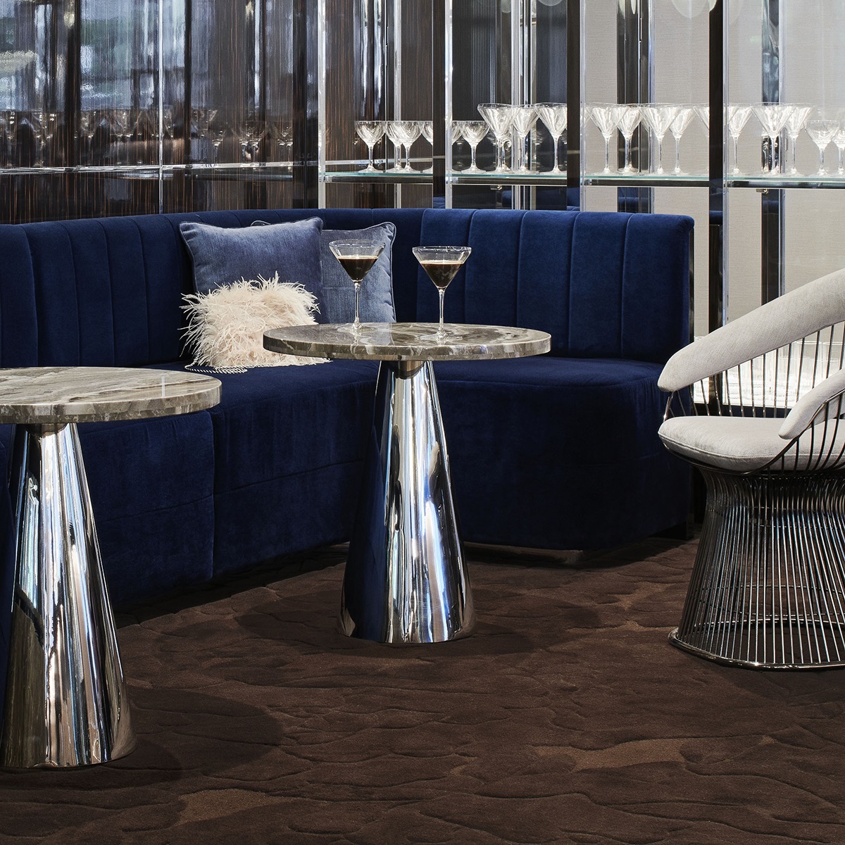 blue velvet seating and chrome tables in the bar with a brown Modieus carpet