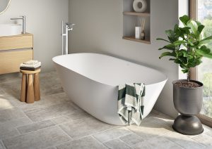 white freestanding bath next to a plant and a window with a wooden stool in the bathroom