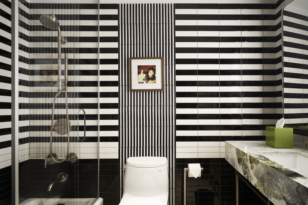 Black and white striped wallcoverinngs in modern bathroom with luxurious marble sinks