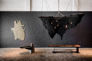 hand crafted and crocheted light sculpture in black fibre by Studio Lloyd against a grey industrial style wall