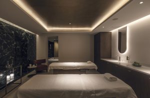 green marble and low lighting in spa area with treatment beds