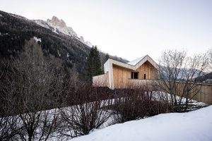 wooden sauna designed by NOA with suspended pathway leading to it from the hillside in Italian Dolomites
