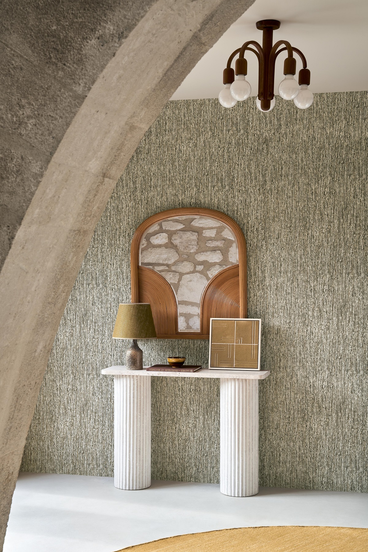 curved arch looking thought to a console table with a mirror and lamp in front of wall in textured wallcovering