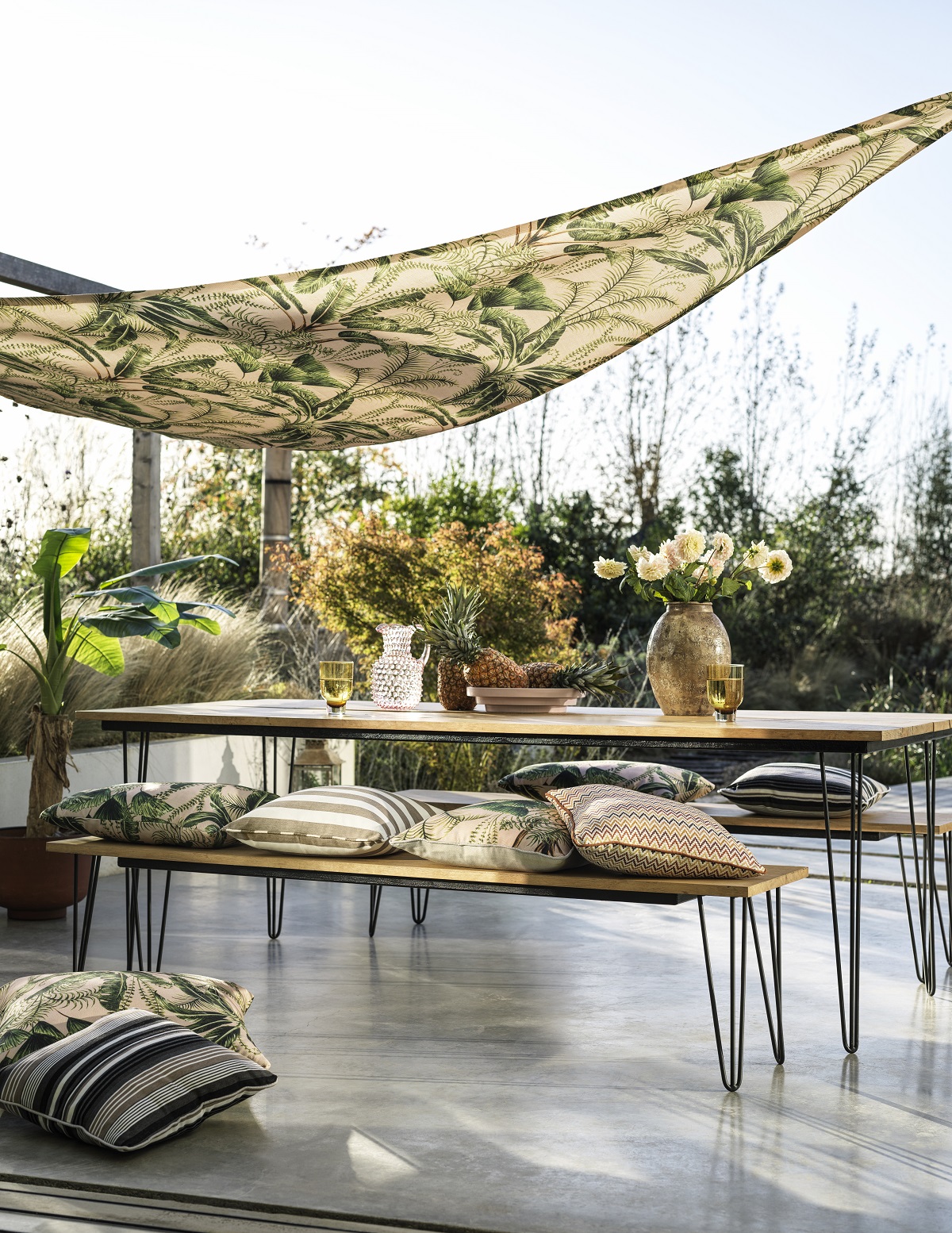 outdoor cushions and shade sail canopy all in a mix of botanical prints and stripes
