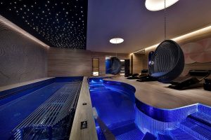 dark blue spa hydrotherapy pool with hanging chair alongside the pool and starlight effect lighting