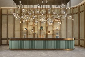 suspended lights above curved reception desk and niches in the wall lit up and displaying objet