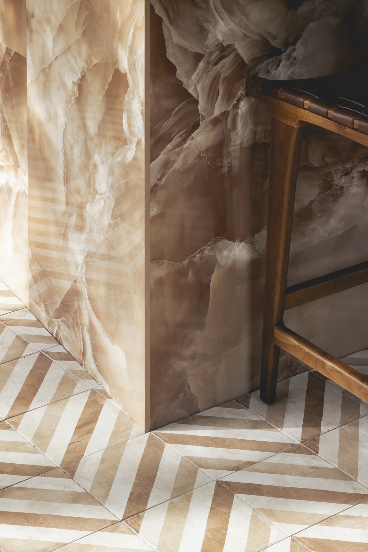 brown marble wall next to brown and white chevron tiled floor