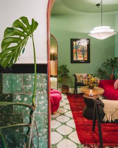 green walls, green patterned tiles on the floor and a rust red carpet in the lobby of the hotel